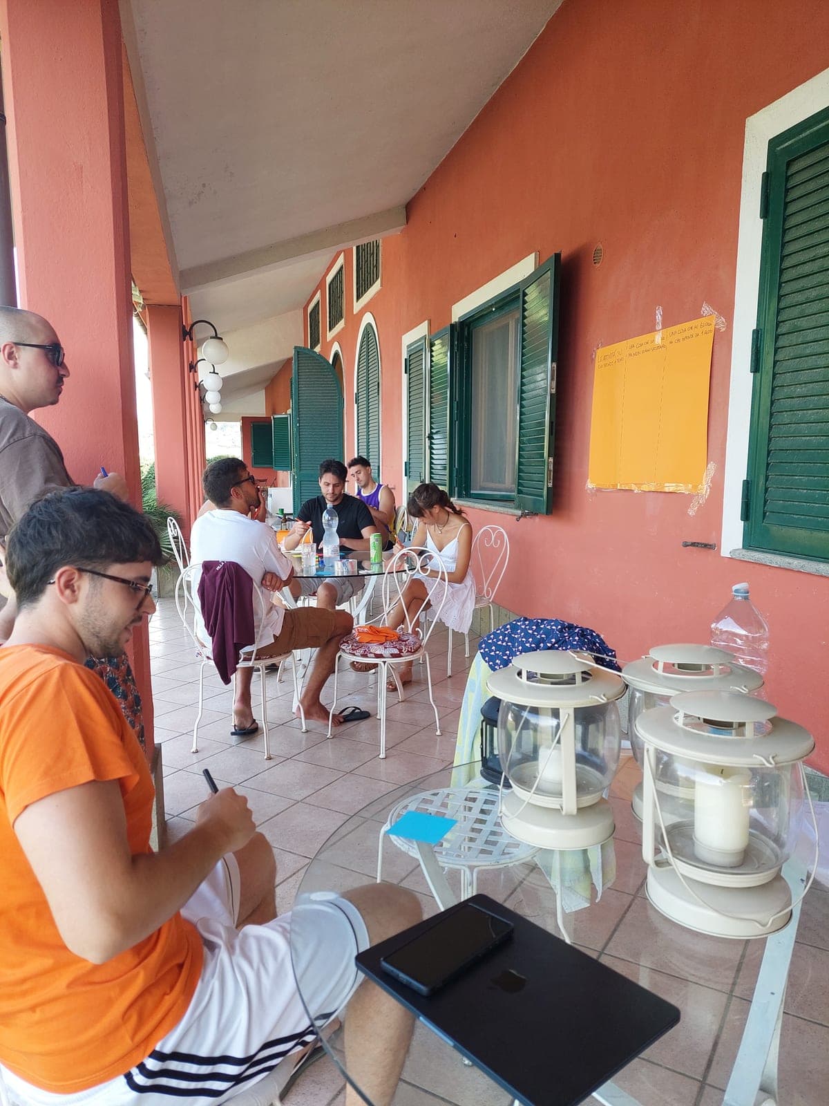 A working session on the villa terrace, with a laptop and sticky notes on the wall