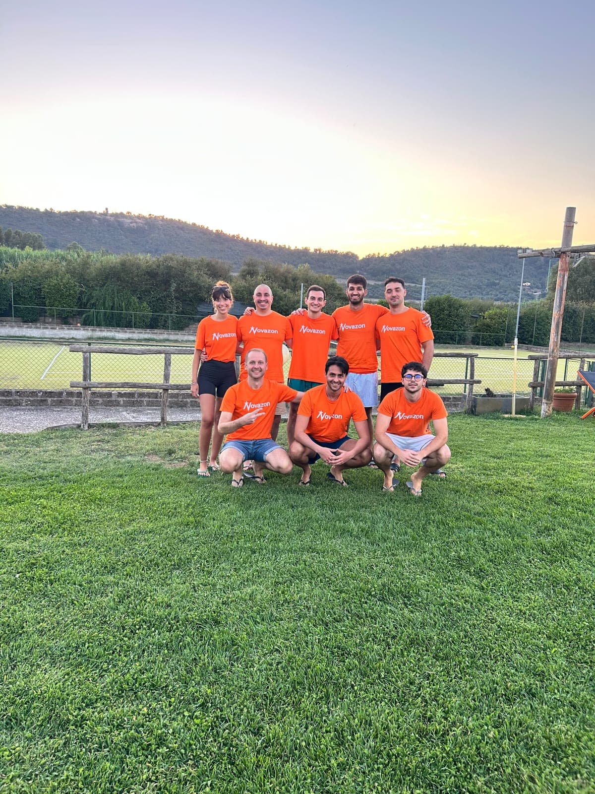 The Novazon team on the villa lawn at sunset, hills in the background